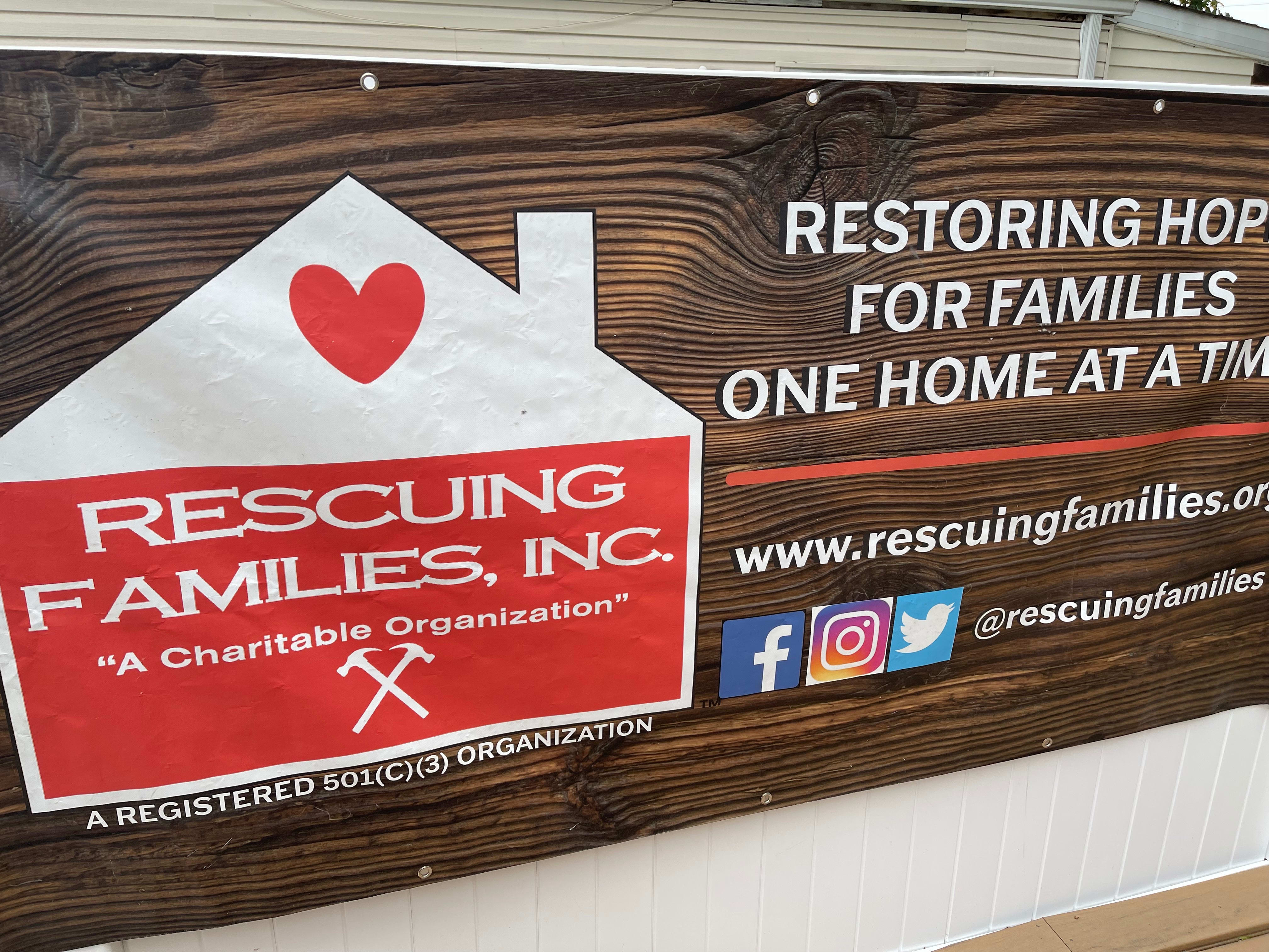 This is a sign for Rescuing Families with house logo and 501-c-3 status