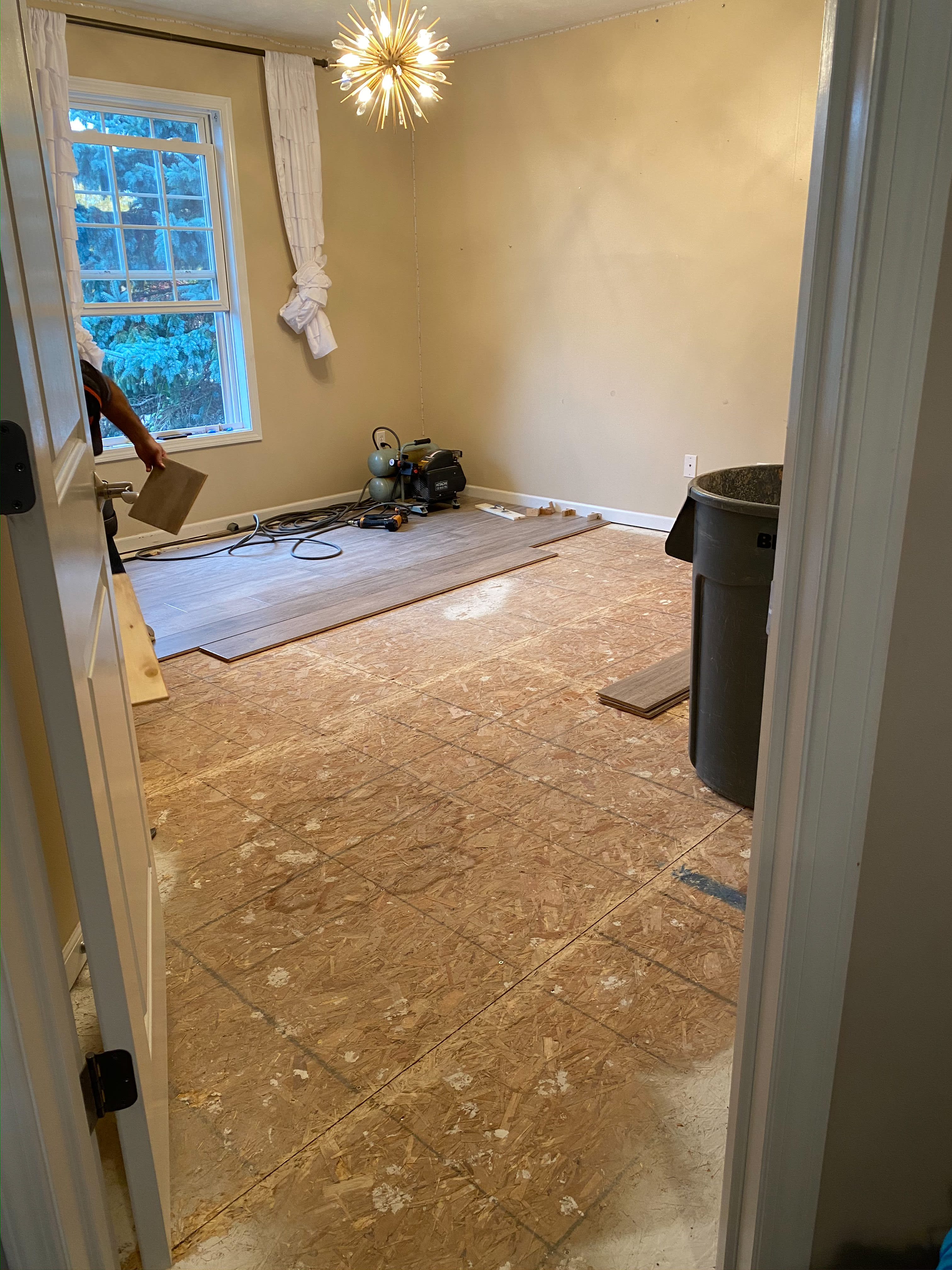 Now the bedroom carpet has been removed showing plywood subfloor underneath and the first few planks of new flooring going down.