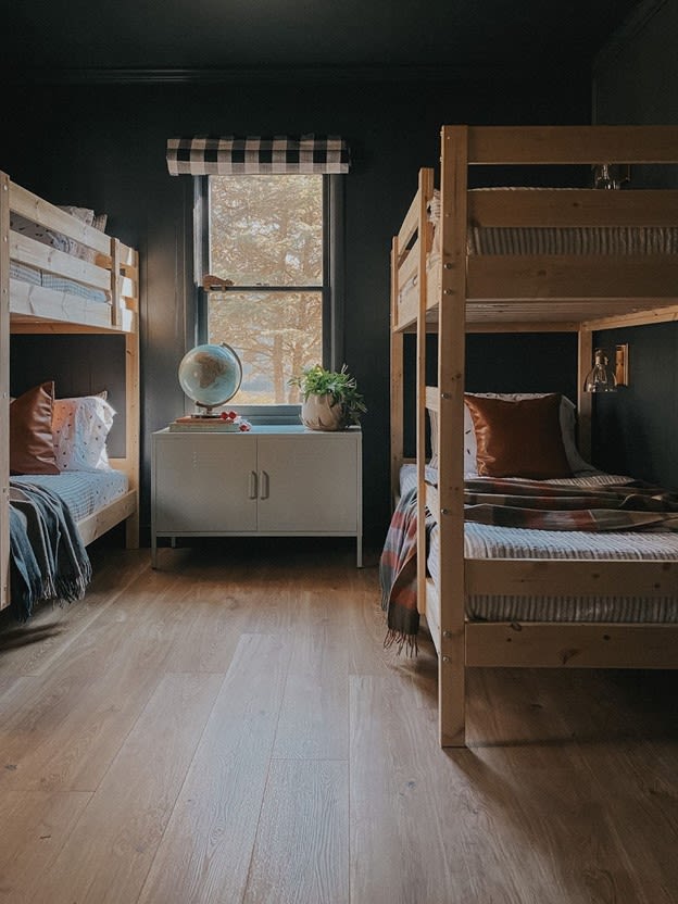 bedroom now has navy-green walls two bunk beds, and new blonde wood flooring.