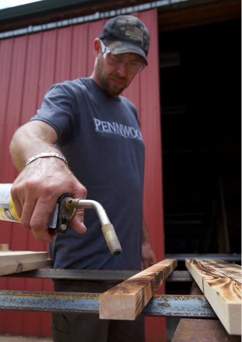 Making US flags of lumber get detailed touches with a blowtorch