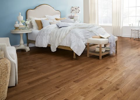 3/4 in. x 3.25 in. Warm Spice Oak Solid Hardwood Flooring in bedroom with pale blue walls and white pucker comforter and beige fabric headboard