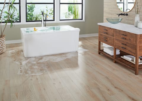 5mm+Pad Cardiff Red Oak Rigid Vinyl Plank Flooring in bathroom with water overflowing from freestanding tub and vessel sink