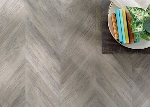 6mm Pacific Coast Oak Chevron Rigid Vinyl Plank Flooring close up of floor with colorful books and plant on end table