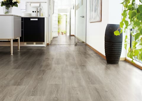 7mm Alpenheim Oak Waterproof Laminate Flooring in kitchen and entryway with tall black vase and glass door