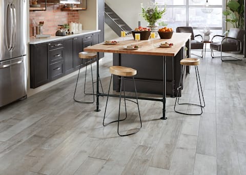 This open kitchen has a perfect gray wood look that is waterproof, with Avella's Metro Concrete Oak Porcelain Tile.