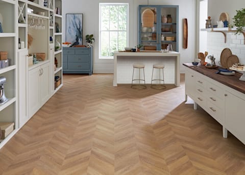 8mm Prospect Park Chevron Waterproof Laminate Flooring in butler's pantry with butcher block counters plus blue cabinets and island with subway tile