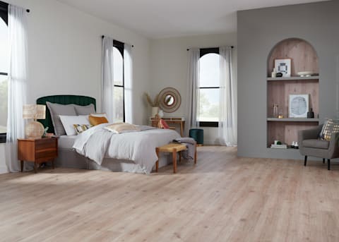 5mm+Pad Rotterdam Autumn Oak Rigid Vinyl Plank Flooring in bedroom with green headboard with light gray bedding and arched alcove with flooring on the wall