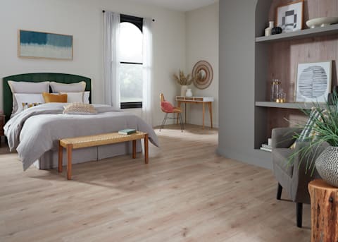 5mm+Pad Rotterdam Autumn Oak Rigid Vinyl Plank Flooring in bedroom with green headboard with light gray bedding and arched alcove with flooring on the wall