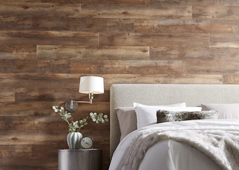 5mm Copper Ridge Oak Click Luxury Vinyl Plank Flooring on wall in bedroom behind bed with beige upholstered headboard and cream bedding plus silver side table and faux fur accent pillow