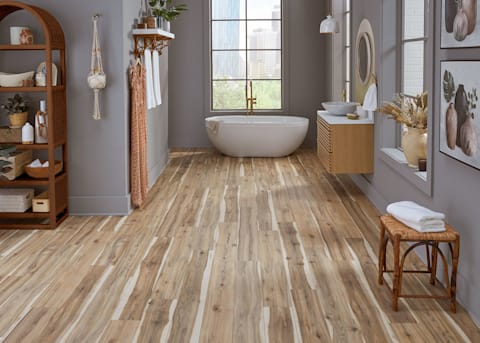 5mm with Pad Royal Hampton Hickory Waterproof Rigid Vinyl Plank Flooring in bathroom with blonde wood floating vanity plus freestanding bathtub and rattan shelves and stool