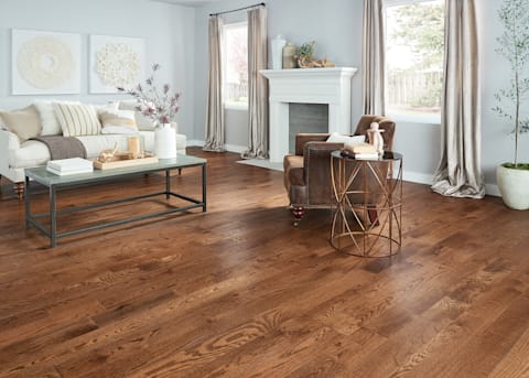 This living room, with a chic-antique style features weathered leather chair, muted tones, and millrun-grade Kensington Oak Distressed Solid Hardwood Flooring.