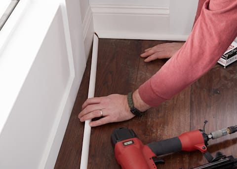 White Flooring baseboard and quarter round being installed after hardwood flooring installation