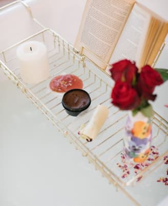 A bath adorned with book, candle, a trio of roses, and Fresh Lush products