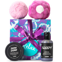 Relax Gift 2020 A purple tie-dye designed gift box with a dark purple bow surrounded by products