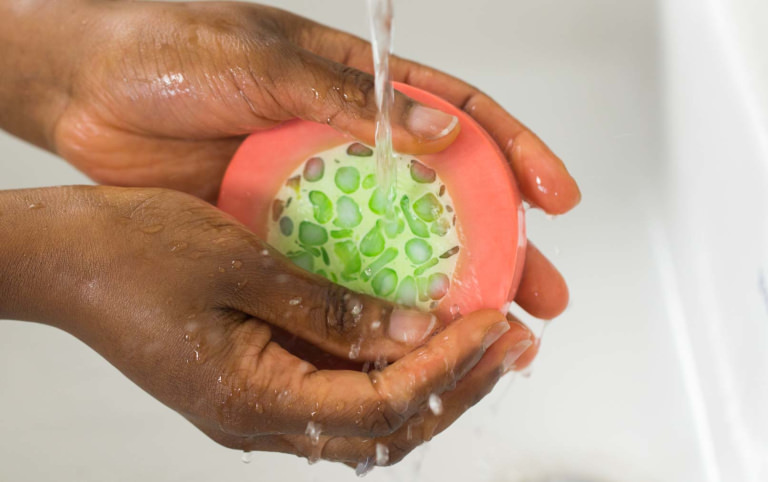 Maypole soap being used A round pink and green soap being used to wash hands in water