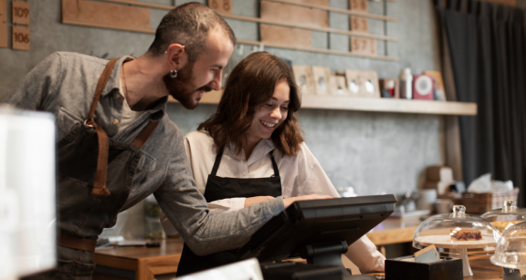 Zwei Personen stehen hinter der Theken und Tippen an der digitalen Kasse.