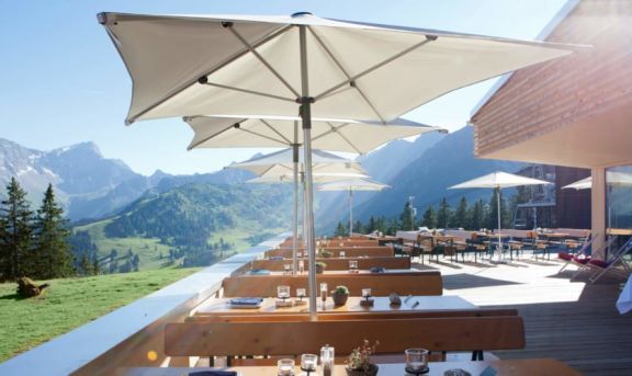 Sonnenschirme von doppler in beige aufgespannt auf einer Terrasse mit einem Alpenpanorma im Hintergrund