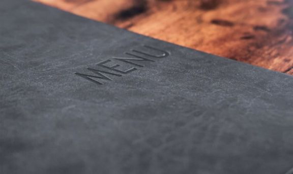 Speisekarte in grau mit Prägung von METAFICH in auf einem Tisch