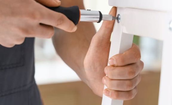 Eine Person schraubt einen Stuhl zusammen