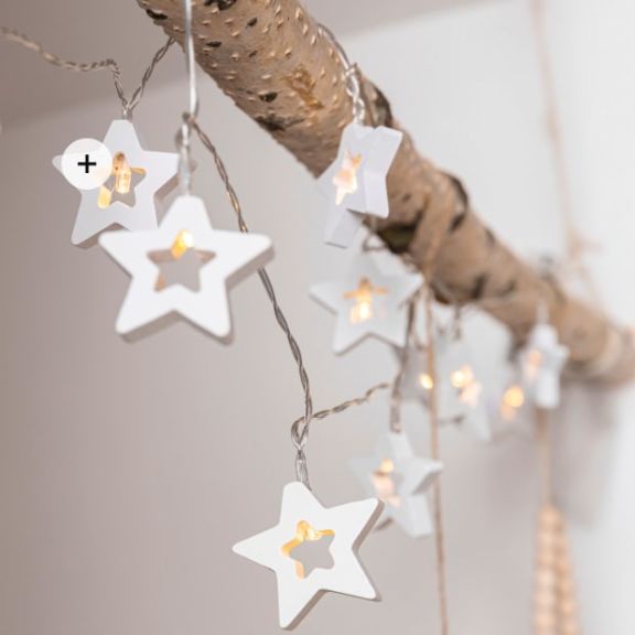 Birkenast eingeklemmt an der Decke zwischen zwei Wänden, dekoriert mit einer sternförmigen Lichterkette.