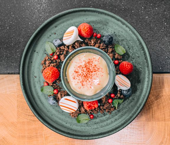 Warmer Lemon-Curd auf gebackenen Schokoladenstreuseln mit frischen Beeren und Baiser-Tupfen