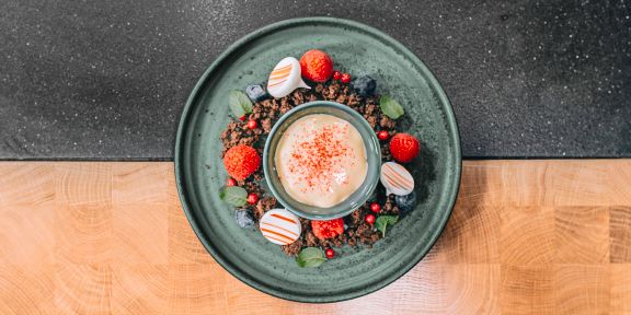Warmer Lemon-Curd auf gebackenen Schokoladenstreuseln mit frischen Beeren und Baiser-Tupfen