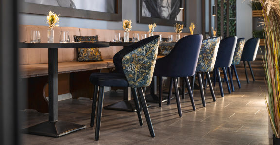 Restaurante con mesas y sillas al interior, las mesas están puestas con manteles en azul claro