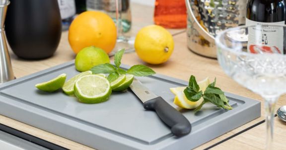 Planche à découper avec couteau et citrons verts frais