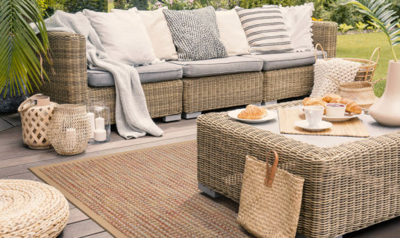 Outdoor Teppich Antigua Sandy-Beach von Grundstoff in hellbraun auf einer eingerichteten Outddor-Loungeecke platziert