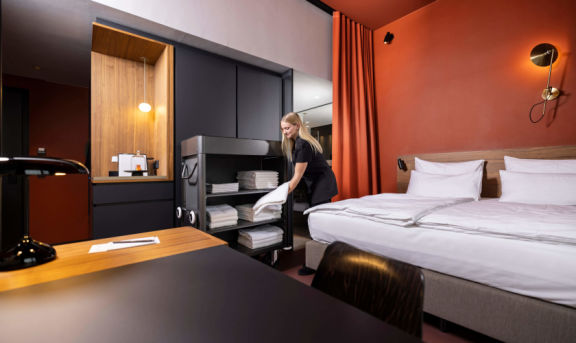 Housekeeping-Dame mit Wagen von Wanzl in einem Hotelzimmer