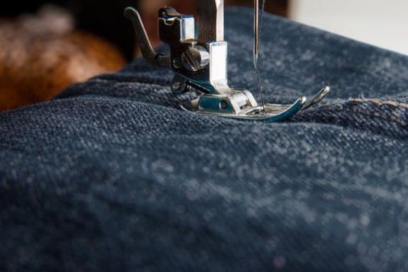 Eine Jeanshose wird mit einer Nähmaschine genäht