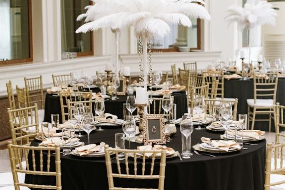 salle avec linge de table noir, assiettes blanches et chaises dorées