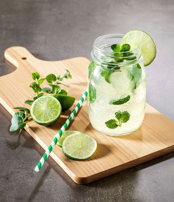 glas auf einem holzbrett mit limetten strohhalm minzeblaetter