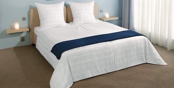 Doppelbett mit weißer Bettwäsche und blauem Läufer