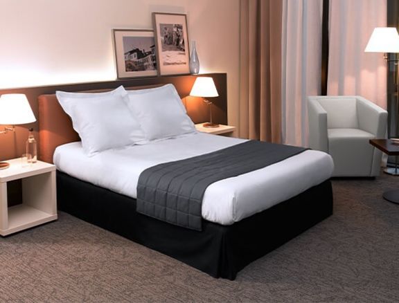 Boxspringbett mit hochwertiger weißer Bettwäsche und schwarzem Läufer