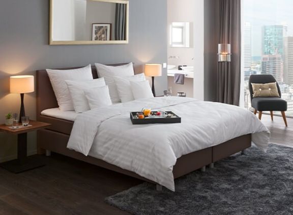 großzügiges Boxspringbett mit hochwertiger weißer Bettwäsche und drei Kissen