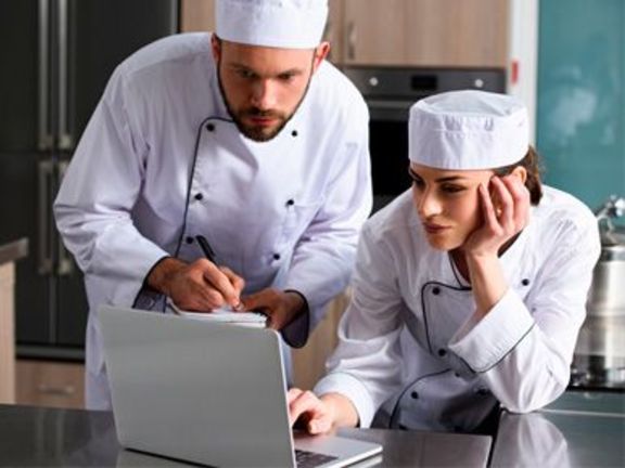 zwei Köche sitzen gemeinsam in einen Laptop