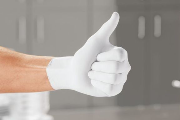 Ein Hand mit Einweghandschuhen, die ein Daumen hoch macht