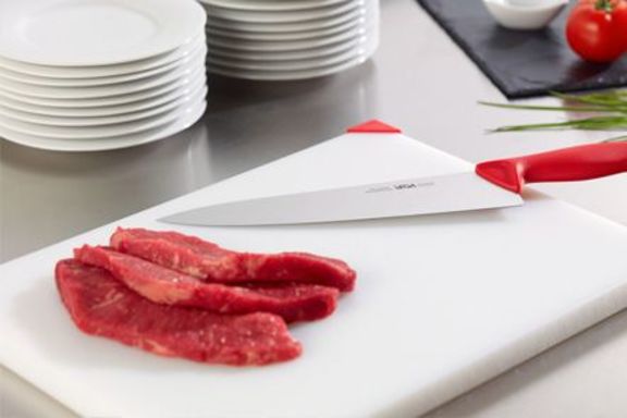 Schneidebrett mit Kochmesser und drei scheiben Fleisch