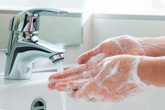 Eingeseifte Hände werden am Spülbecken mit laufendem Wasser gewaschen