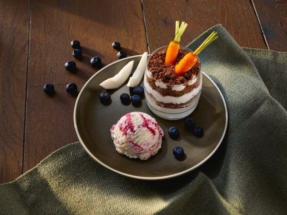 Dessert met mousse en ijs op een donkerbruin bord