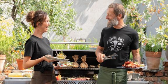 Zwei Personen im Garten vor einem Grill