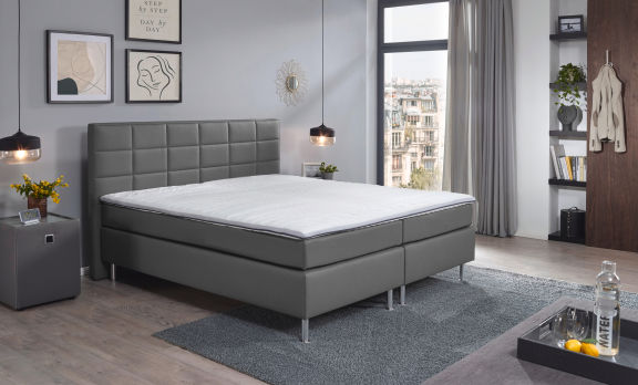 großzügiges Boxspringbett mit weißer Bettwäsche und braunen Kissen