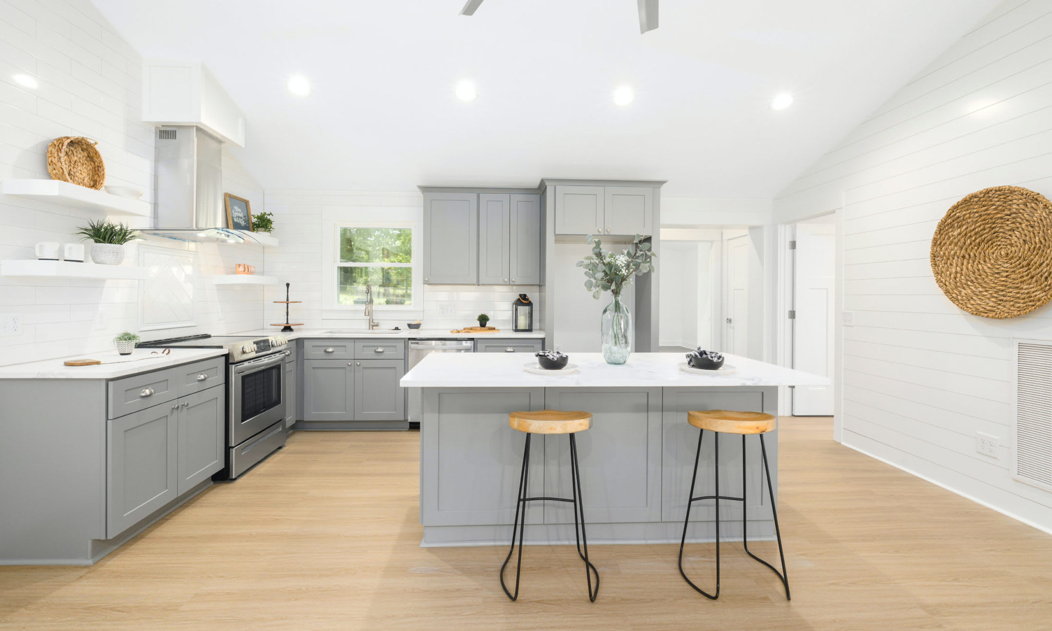 A modern kitchen with a large center island and two stools.