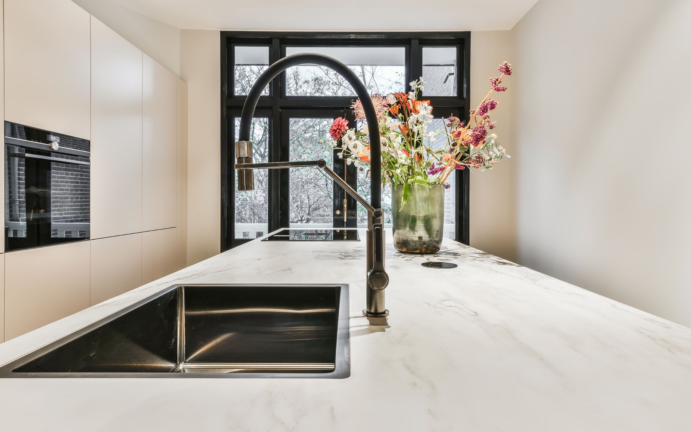 A modern kitchen countertop with a black faucet and a stainless steel sink