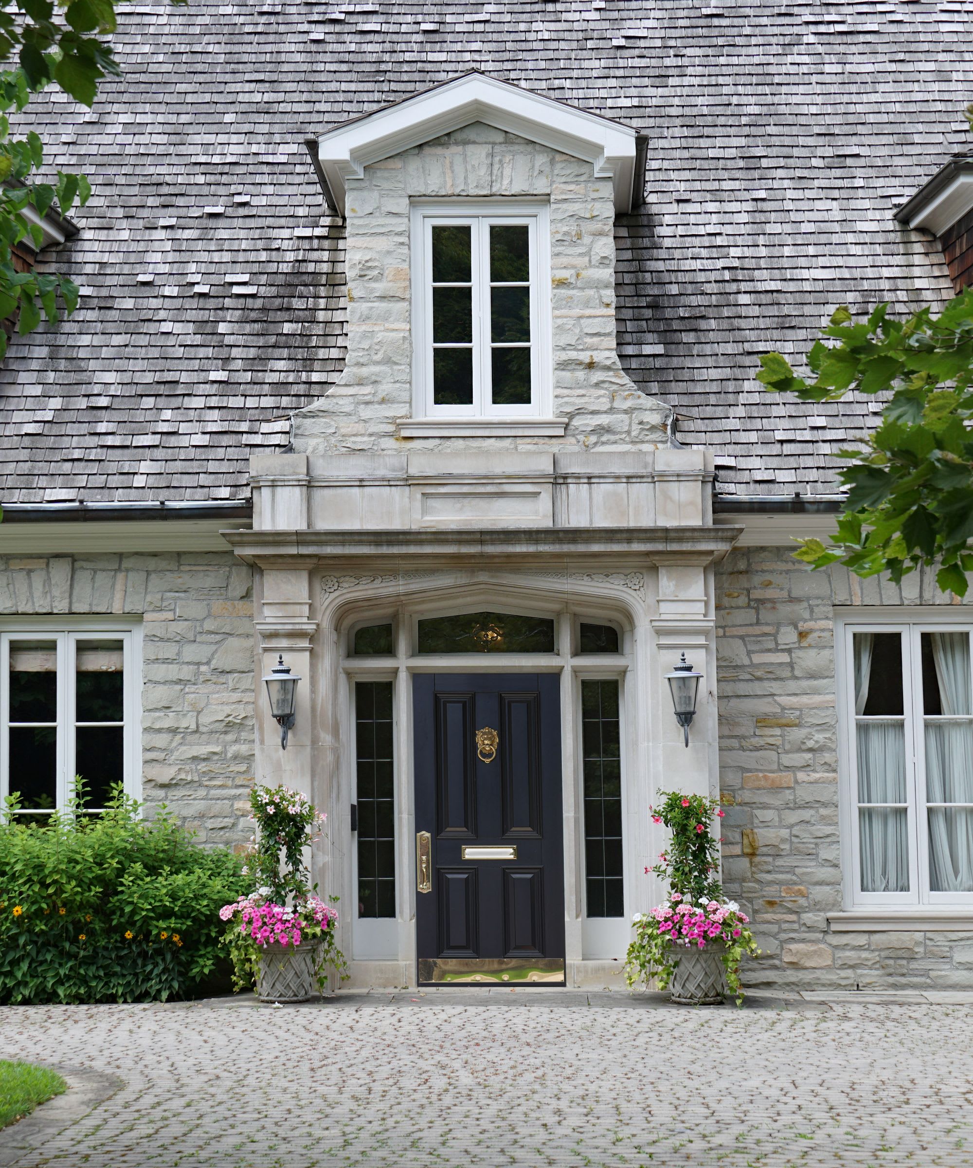 Stone exterior of a stately home with black door and white windows.