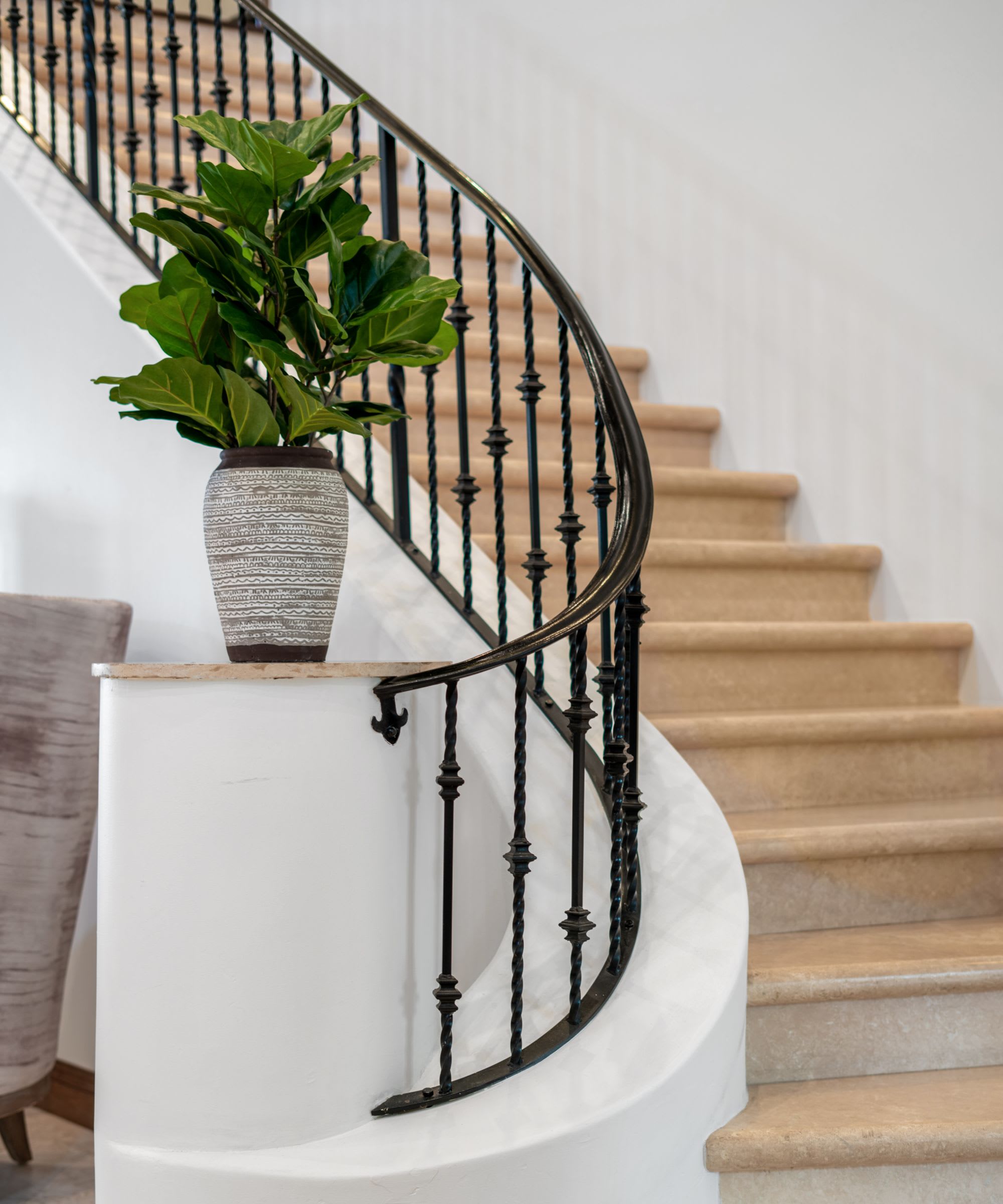 A curved staircase with wooden steps and a black wrought iron railing
