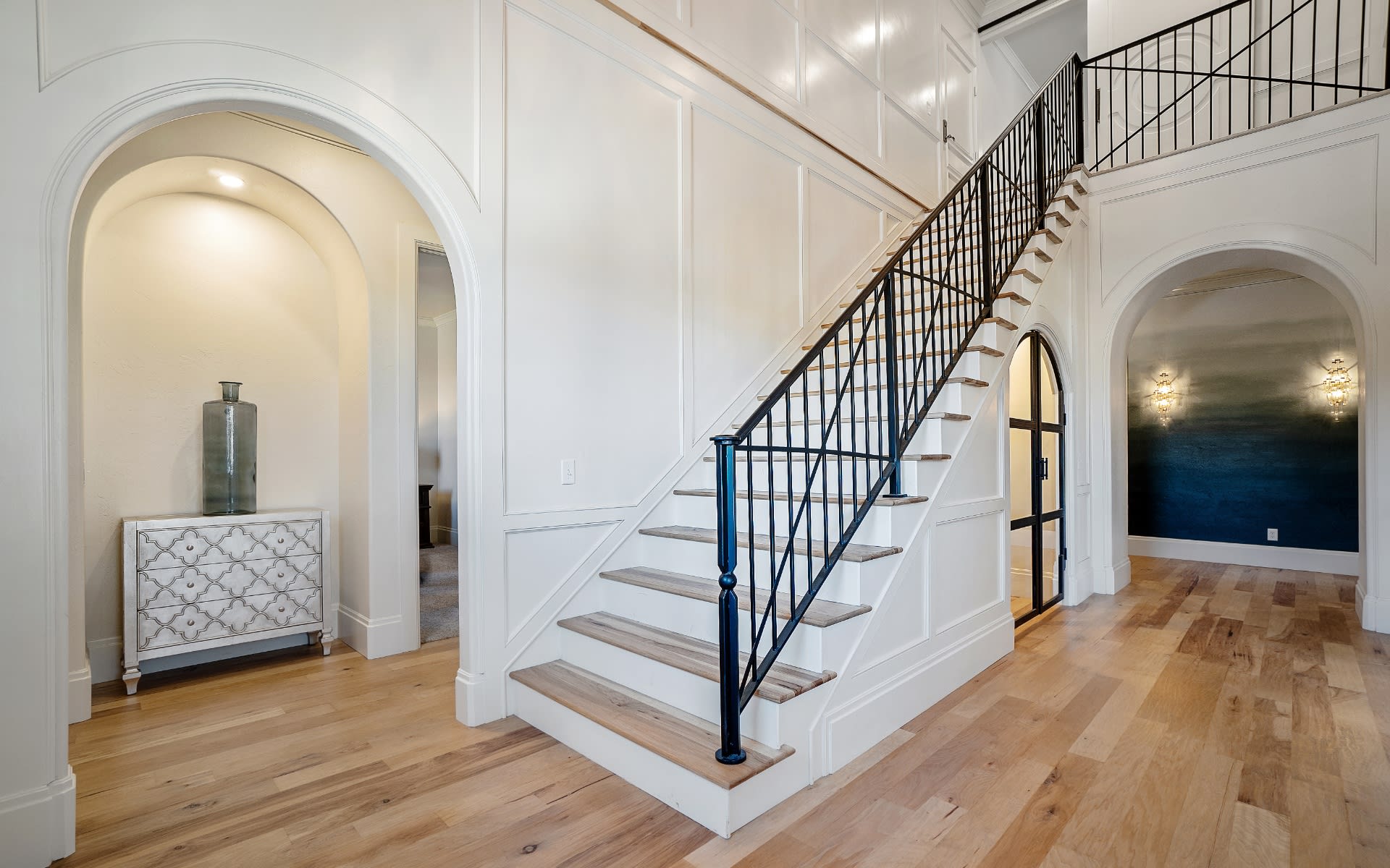 A staircase with light wood treads and black metal railings.