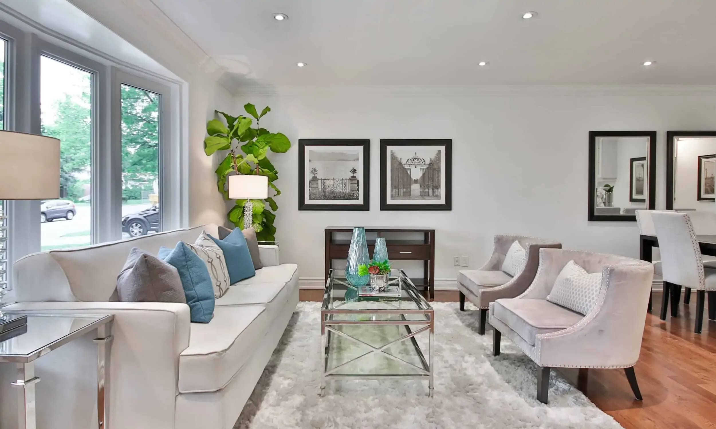 A brightly lit living room with a comfortable-looking couch, two armchairs, a coffee table, and a rug.