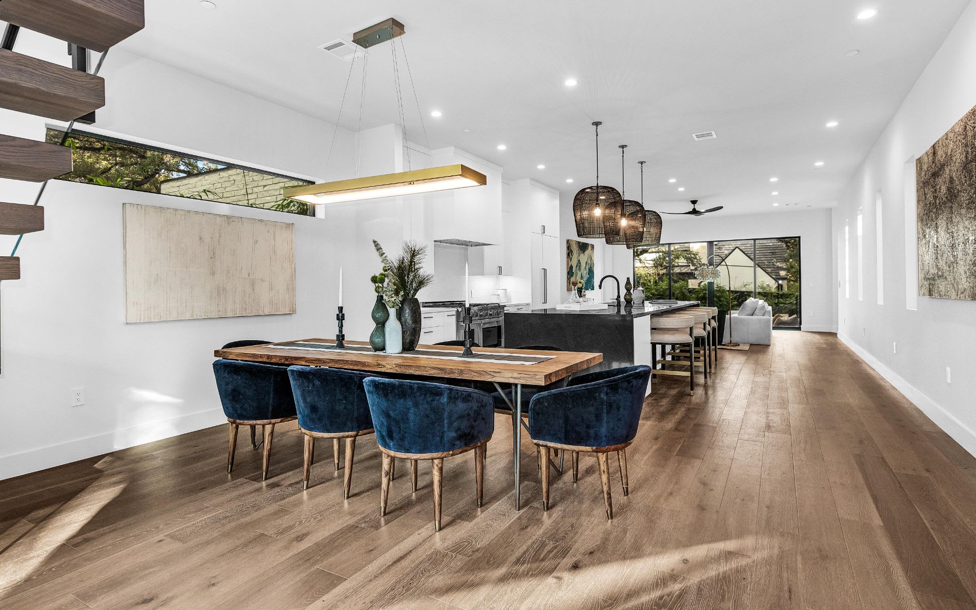 A modern dining room with a long wooden table and blue velvet chairs.